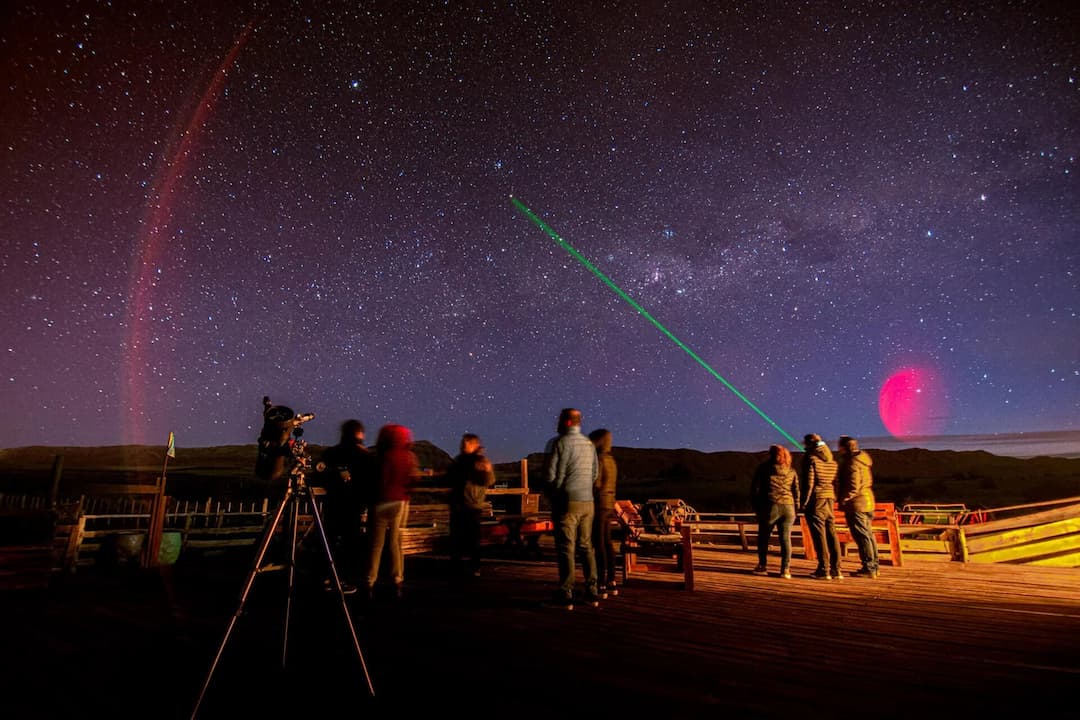 Group observing the night sky with a laser pointer on an El Calafate astronomy tour.